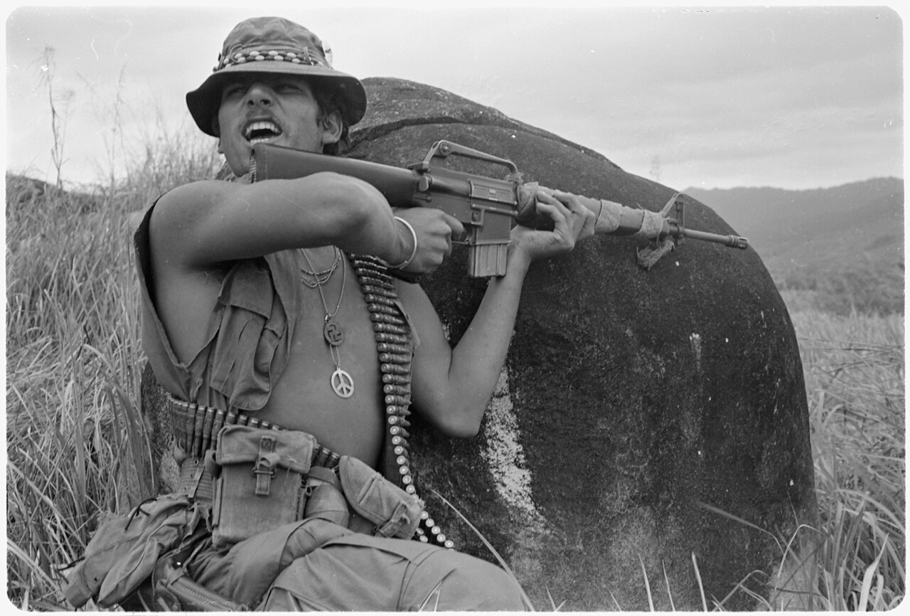 A U.S. soldier in Vietnam wearing various amulets, including the "peace symbol" and the Buddhist swastika (1971 photograph)